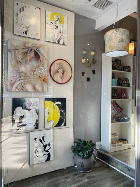 Image shows paintings mounted on a wall. the artwork features colorful figures with lots of curling lines and yellow, red and purple accents.